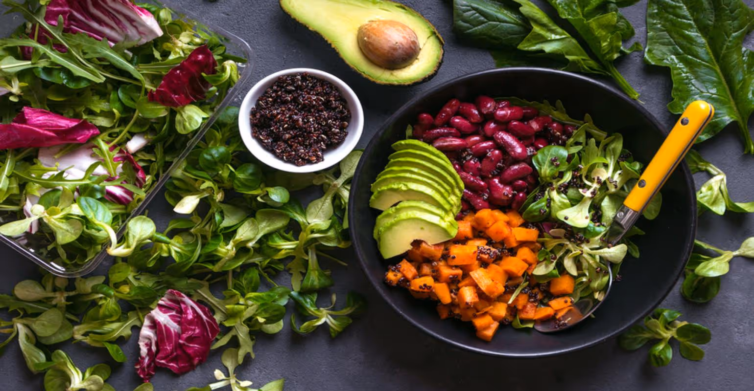 A vegan food bowl with vegetables and fruits around it