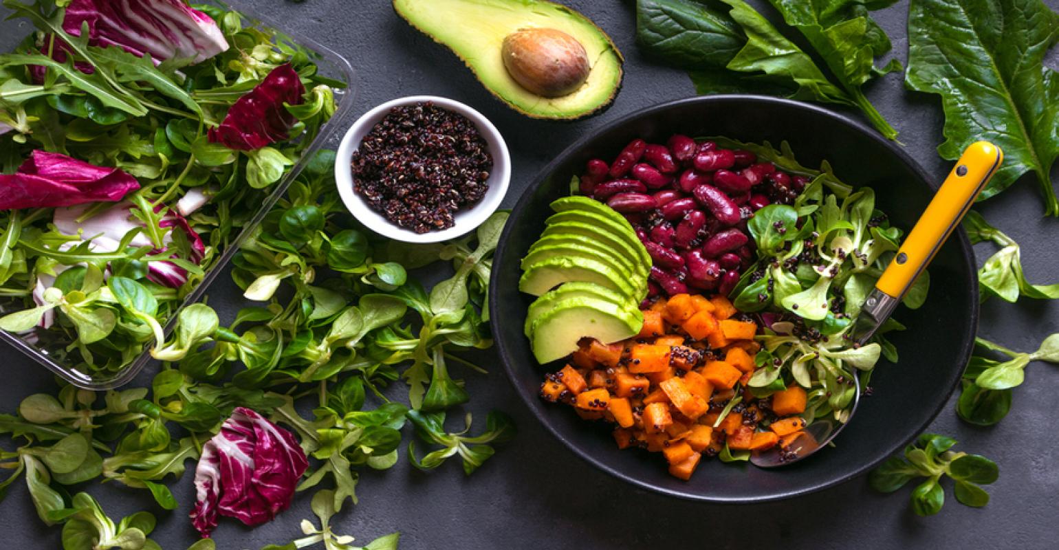 A vegan food bowl with vegetables and fruits around it