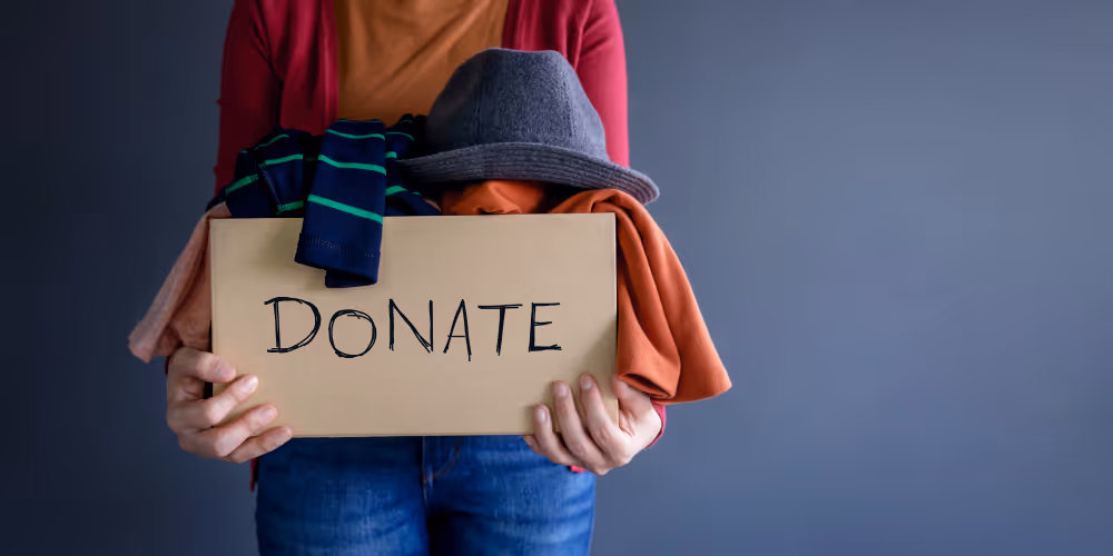A woman holding a box of clothes to be donated for a sustainable lifestyle