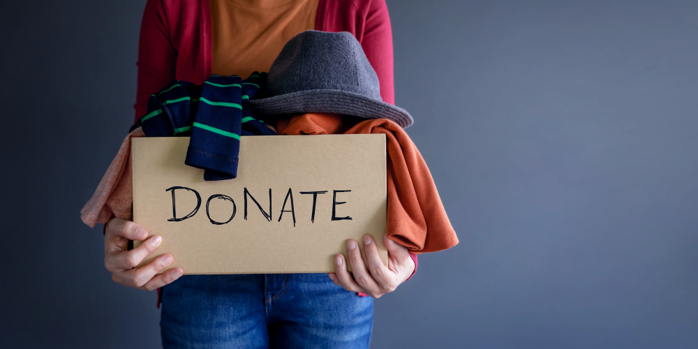 A woman holding a box of clothes to be donated for a sustainable lifestyle