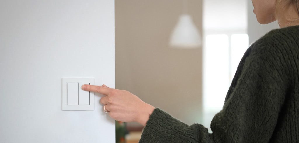 A woman switching off the lights before leaving the room as a part of a sustainable lifestyle