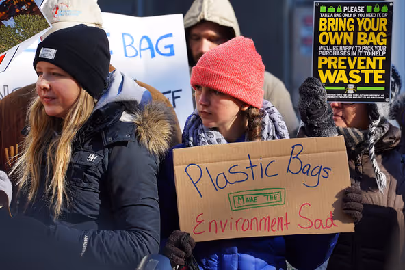 Girl holding up a poster saying"Plastic Bags Make the Environment Sad"