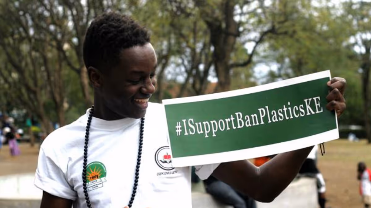 A man in Kenya holding up a banner saying #ISupportBanPlastic