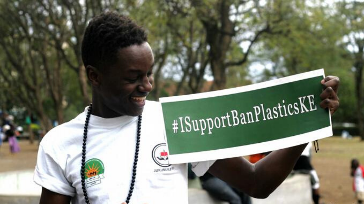 A man in Kenya holding up a banner saying #ISupportBanPlastic
