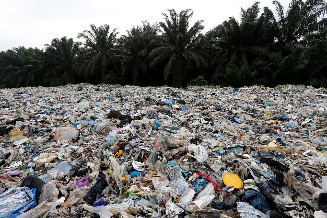 A beach coast covered with plastic waste  with palm tress in the background