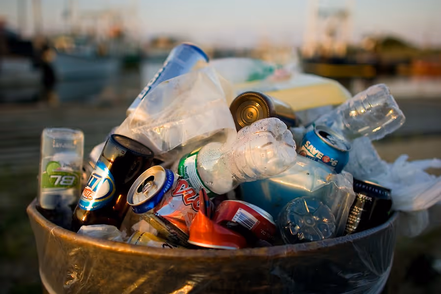 A trash can full of beverage cans and bottles which are one of the major contributors to plastic pollution