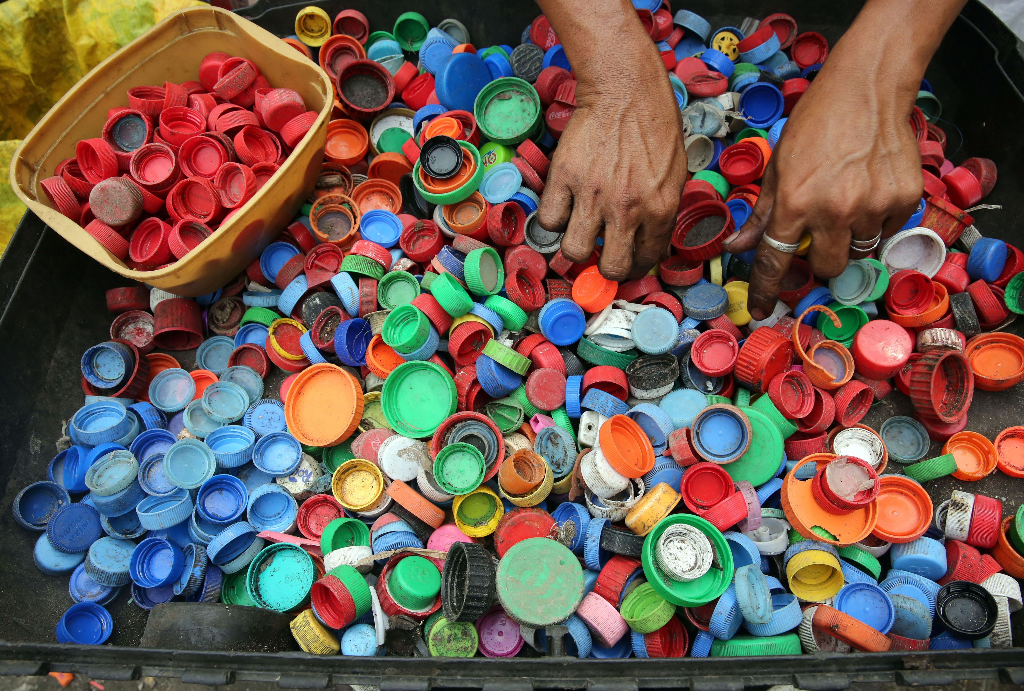 A man sorting through bottle and container caps which are one of the major contributors to plastic pollution