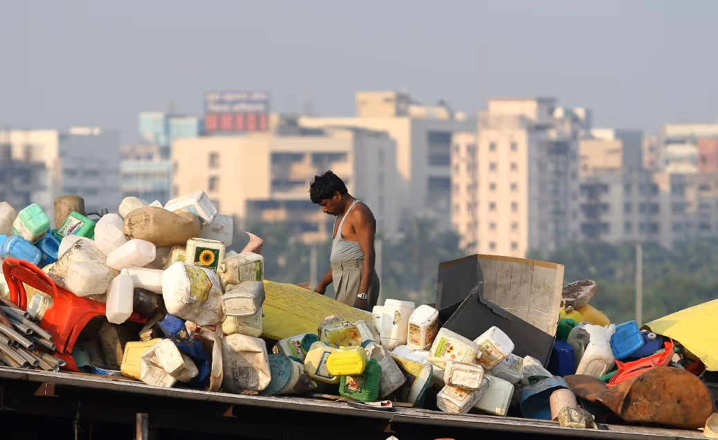 A man standing behind a garbage dump