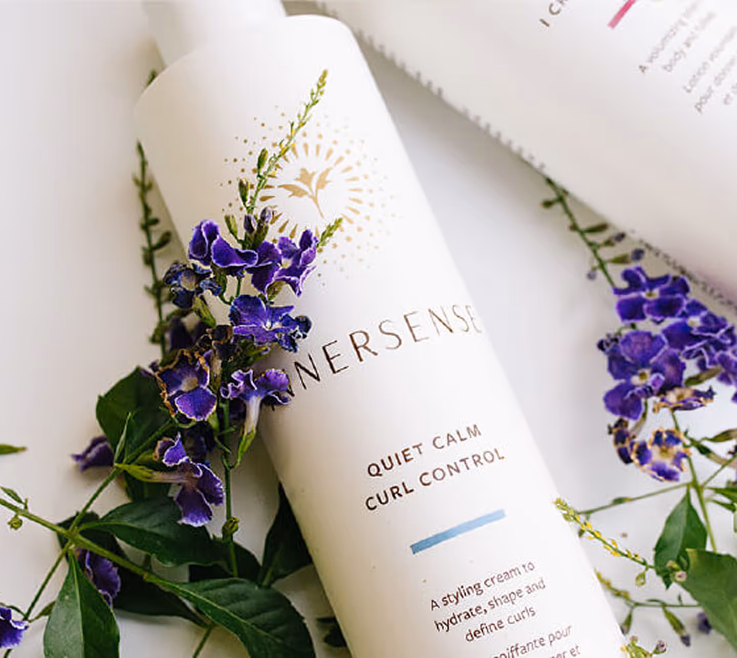 a white bottle with a label on it next to a purple flower