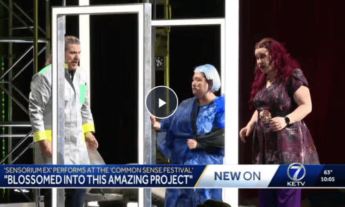Screenshot of a news broadcast showing three actors in the middle of a performance. Text says, “‘Sensorium Ex’ Performs At The ‘Common Senses Festival.’ ‘Blossomed Into This Amazing Project.’”