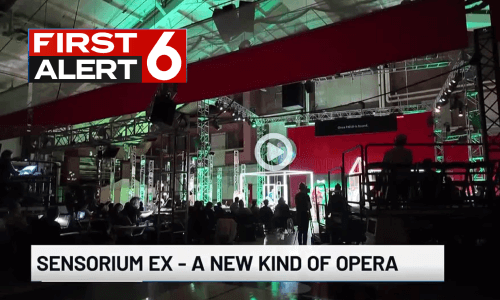 Screenshot of First Alert 6 news broadcast of the set of “Sensorium Ex.” Text says, “Sensorium Ex- A new kind of opera.”