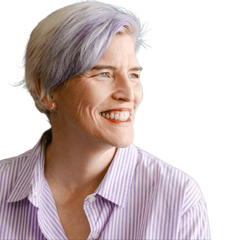 A white woman with pixie cut silver hair with purple tips, wearing a white and purple striped button up. She is smiling and looking away from the camera. The background is green.