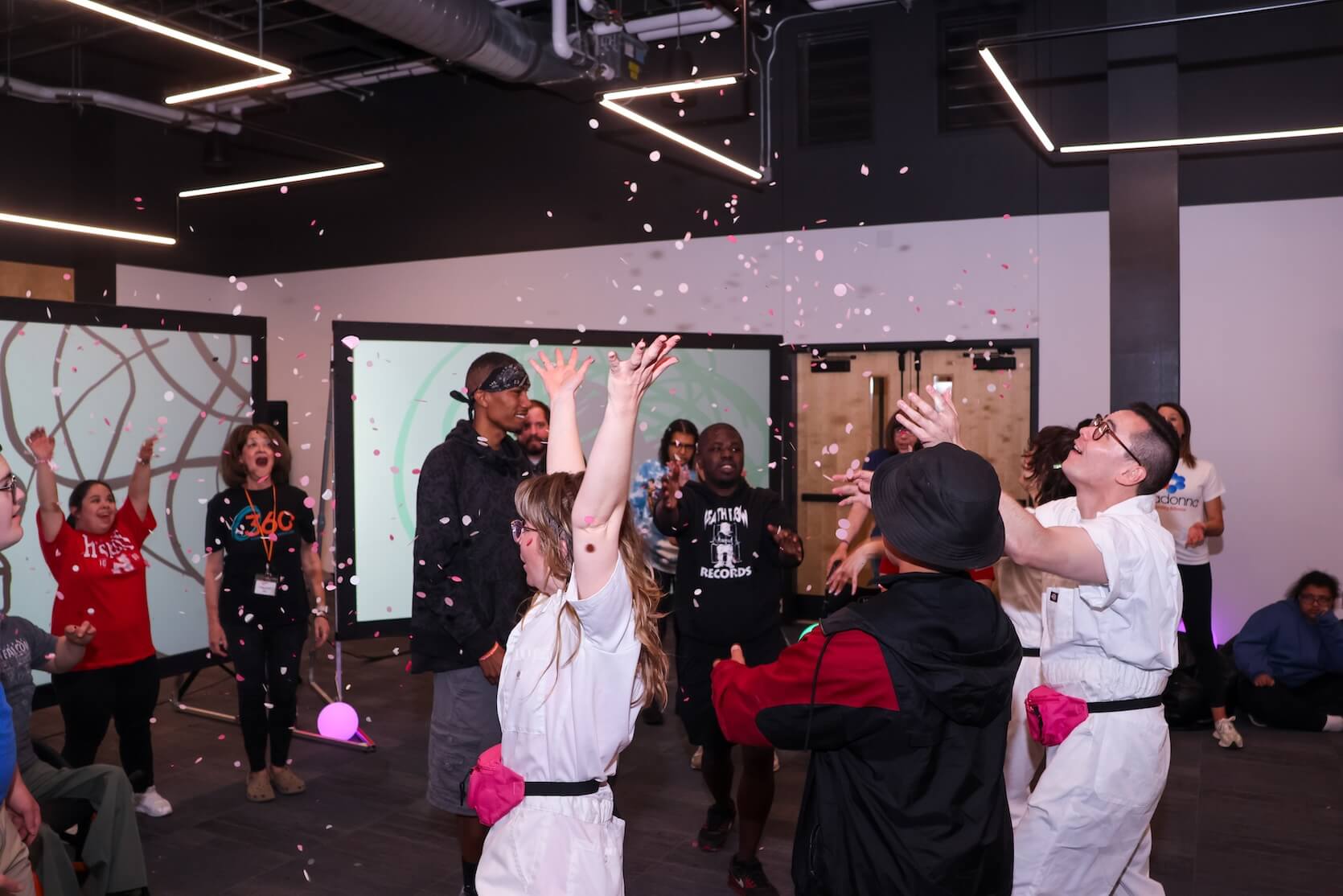 A group of people laughing and smiling as confetti drops down.