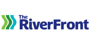 The Riverfront logo: “The Riverfront” in bold blue text, and a light green, dark green, and turquoise squiggly lines on its left hand side
