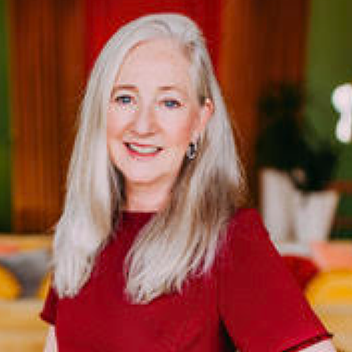Woman with blonde hair, and a red shirt smiling. 
