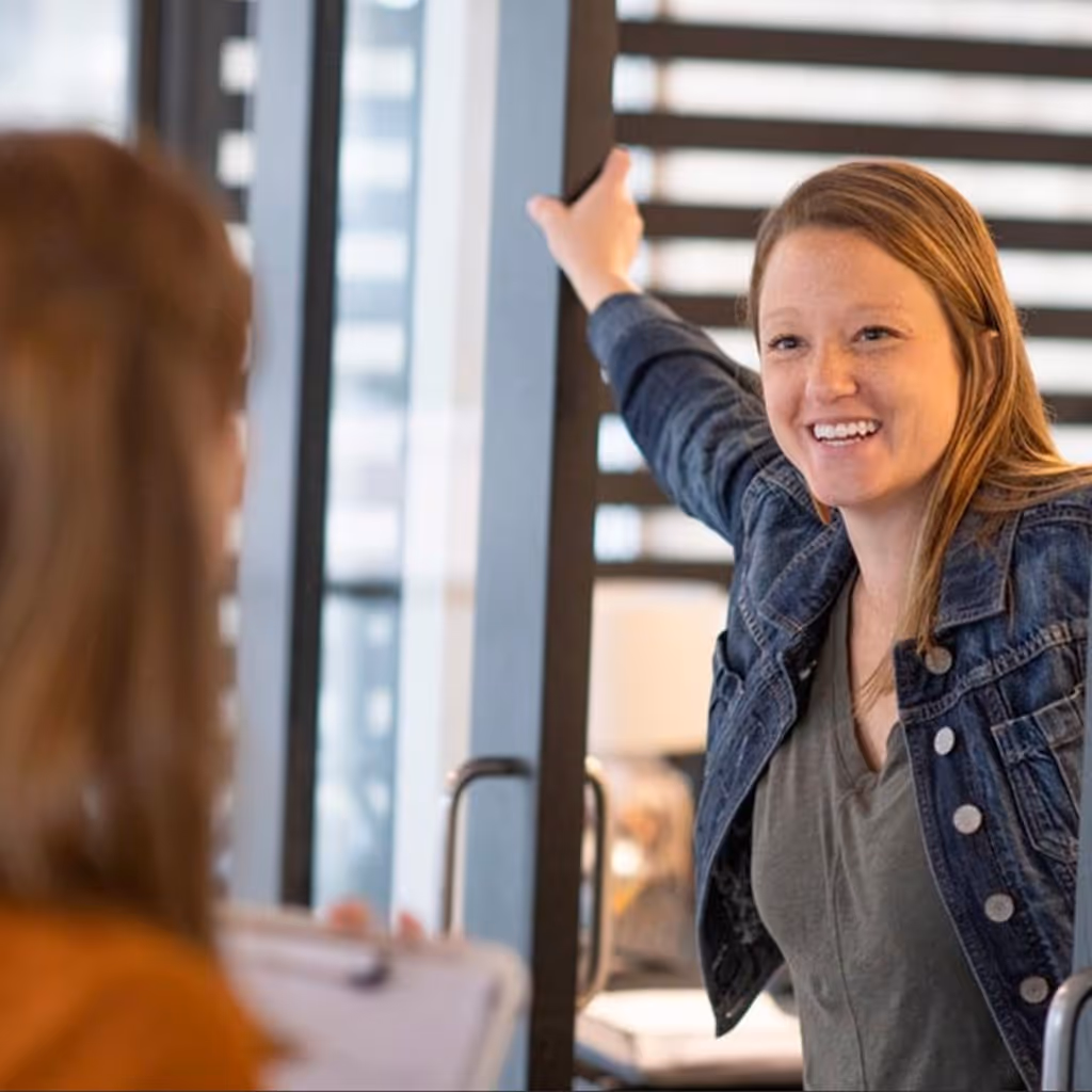 An employee leaning on a doorframe talking to co-worker.