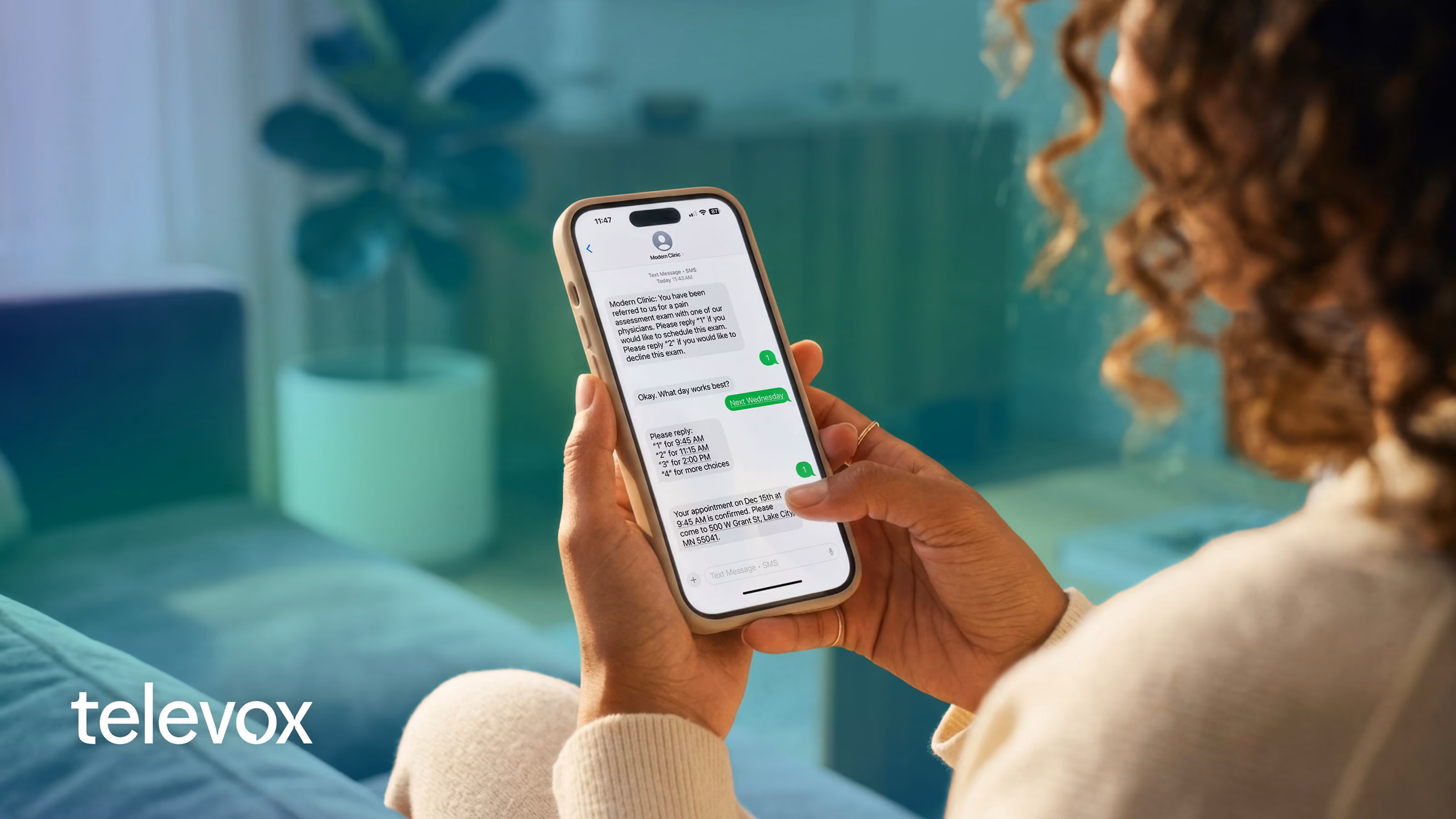 Person holding a phone showing a text conversation confirming a medical appointment from Modern Clinic.