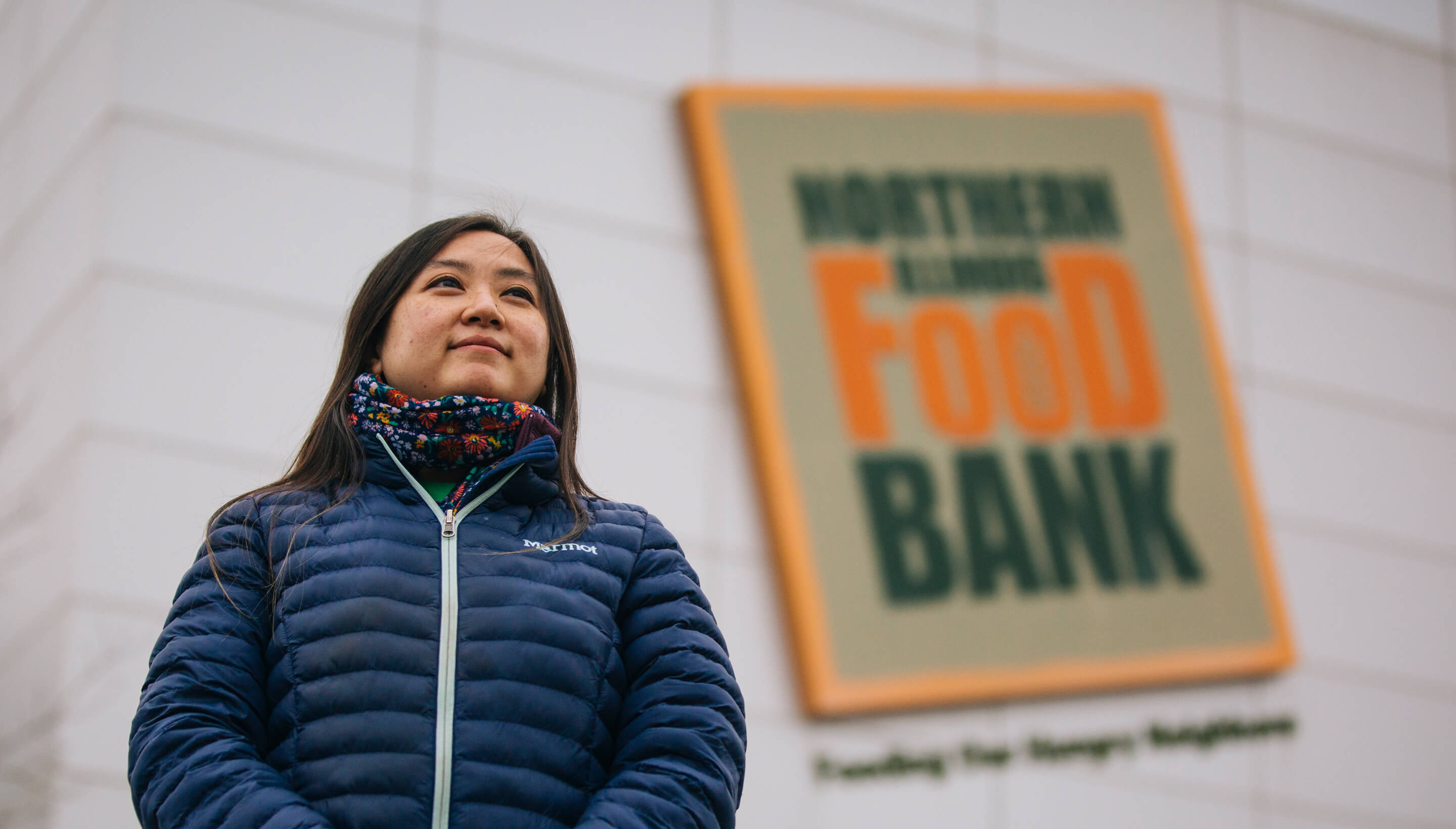 Woman in front of the Food Bank sign