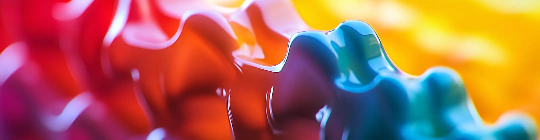 Abstract, multicolored plastic waves with vivid gradients in red, orange, yellow, blue, and green, giving a shiny, fluid appearance.