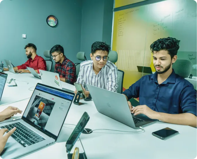Team members collaborating on laptops in an office