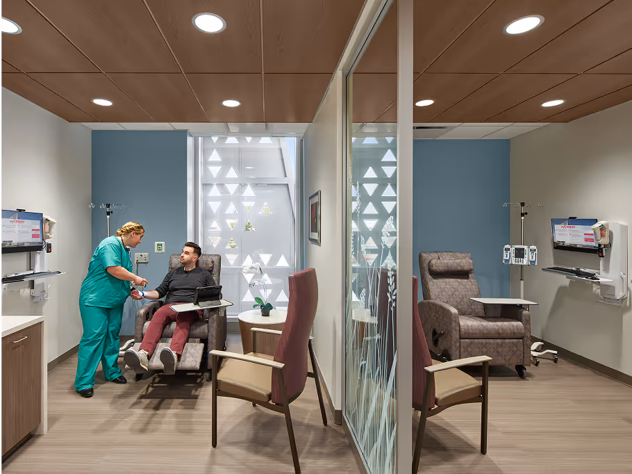 Healthcare treatment room with a patient and medical staff member.
