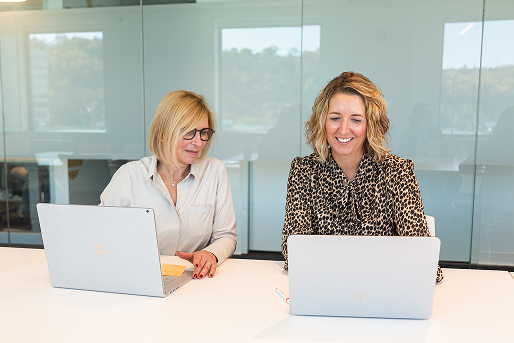 Two colleagues working together on laptops.
