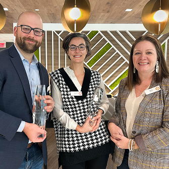 Three team members holding award trophies.