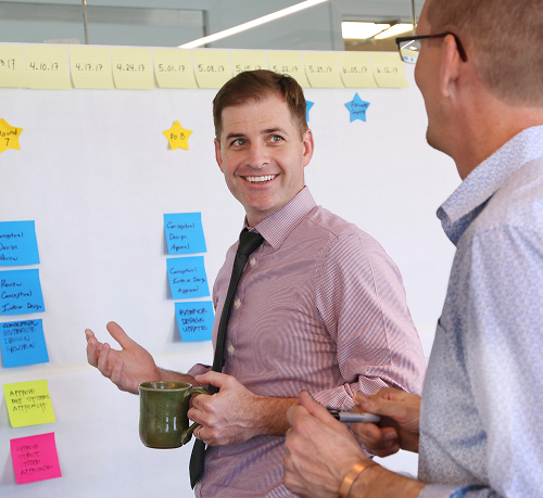 Team members discussing plans at a project board.