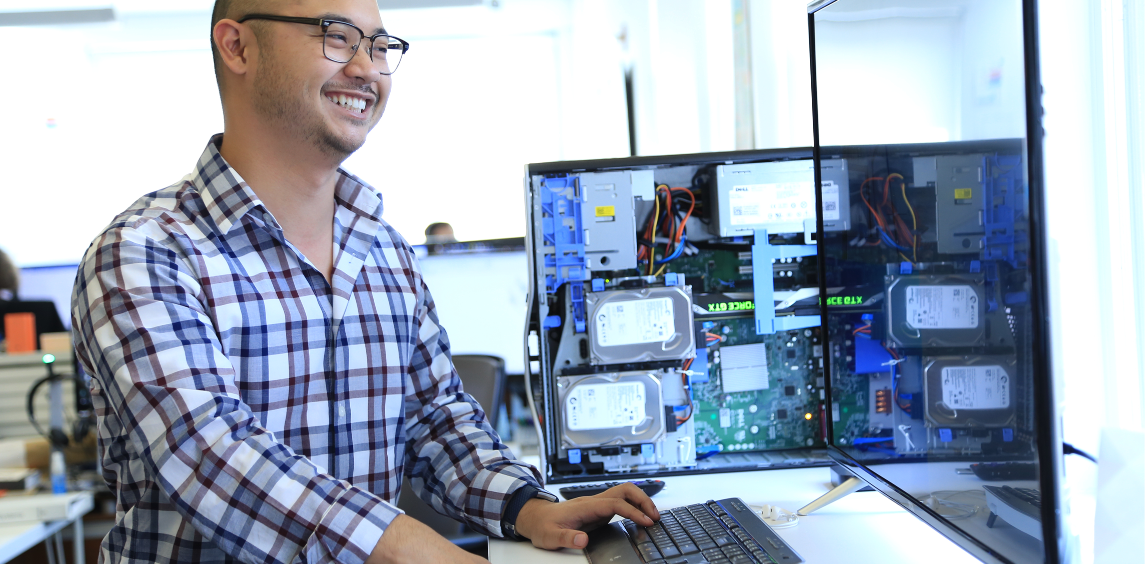 Person working at a computer with open hardware components.
