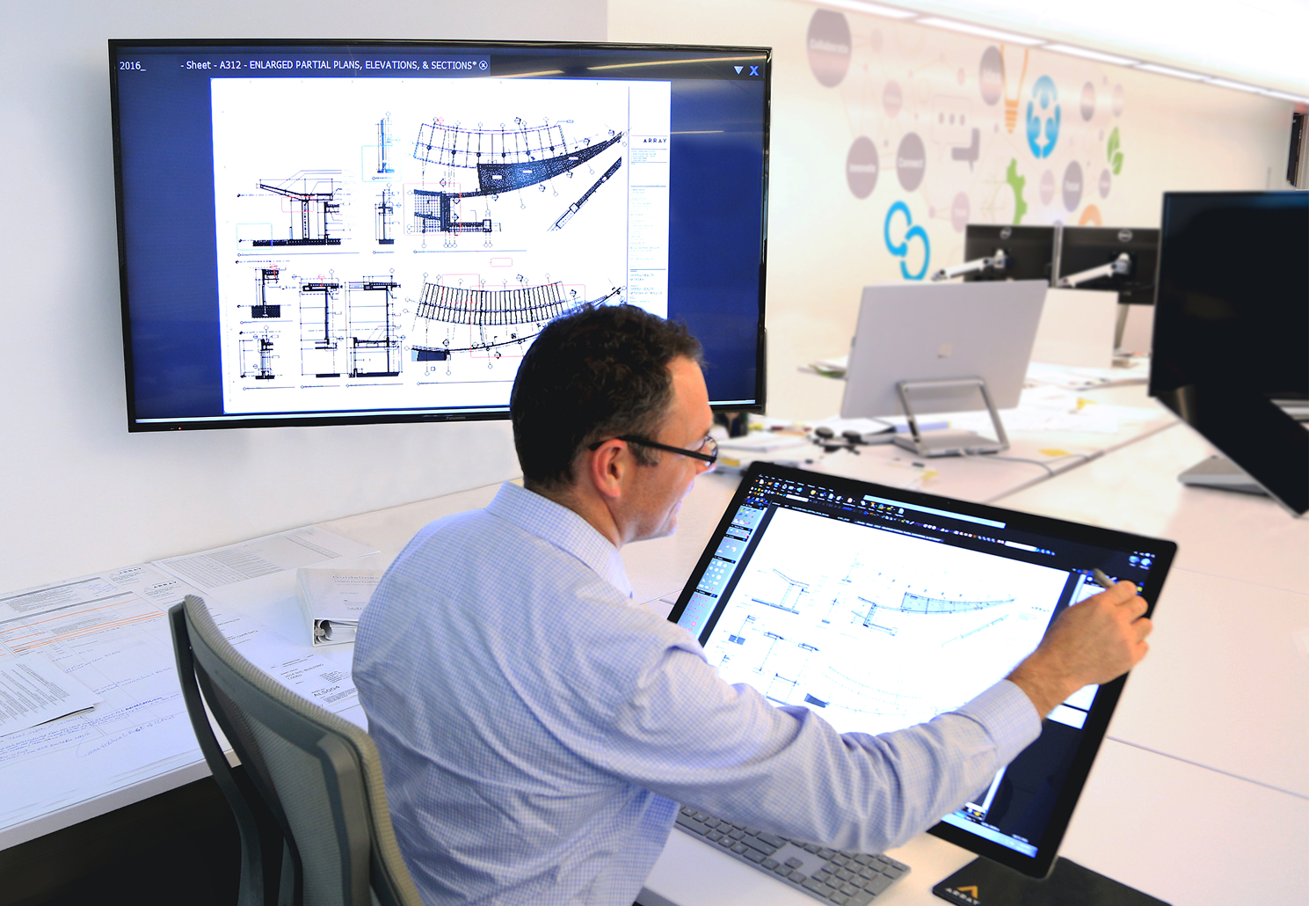 Architect reviewing digital building plans on a touchscreen workstation.