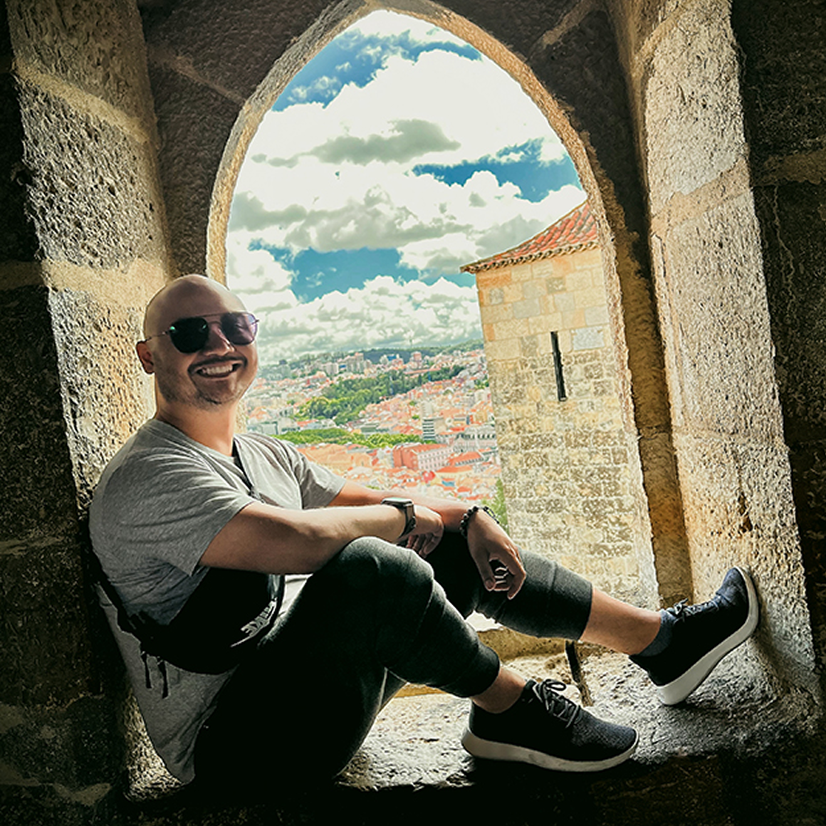Team member sitting in a stone archway overlooking a cityscape.