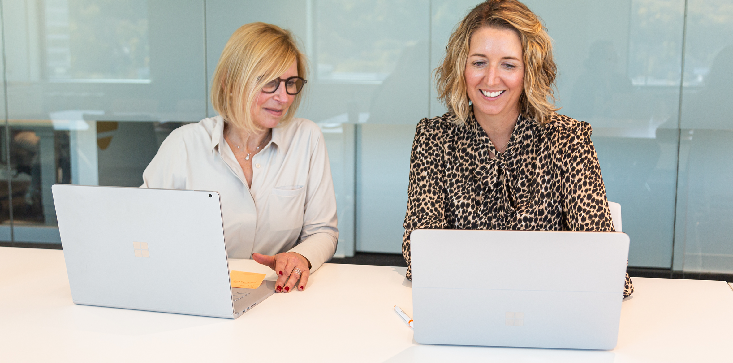 Two colleagues working together on laptops.
