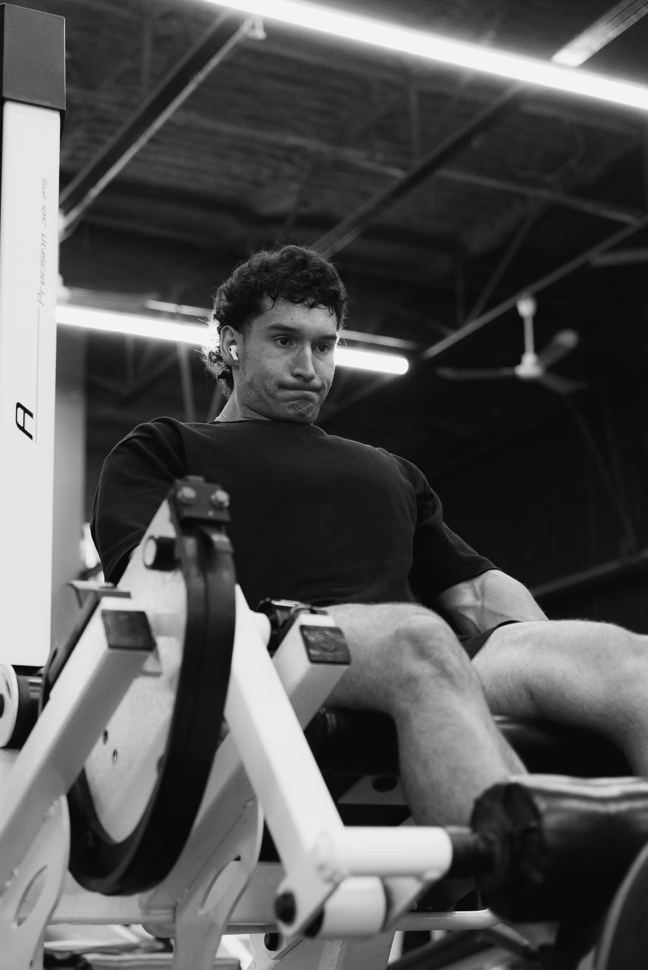 Entraineur qui utilise une machine a jambe au gym.