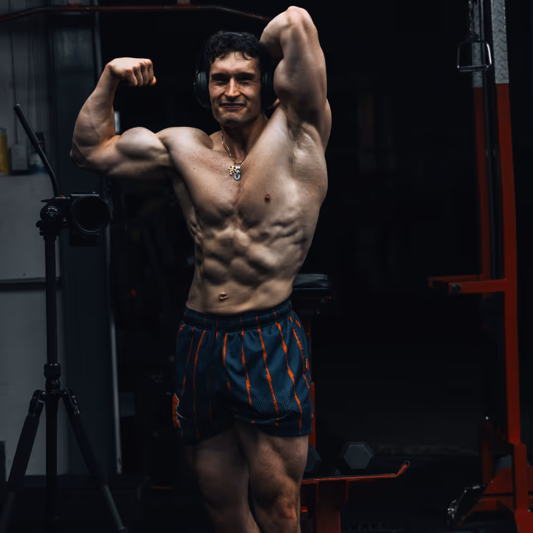 Coach de gym qui fait une pose devant le mirroir. Il est très musclé et découpé.