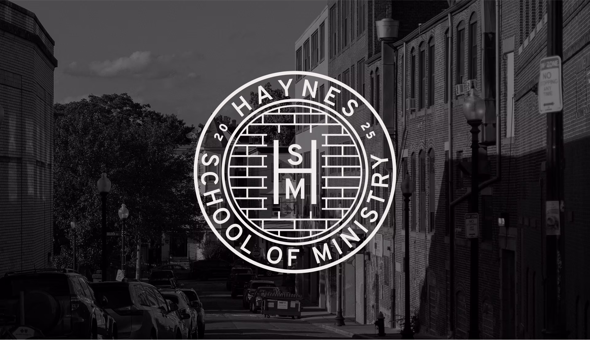 The HSM crest over a black and white image of a street in Boston