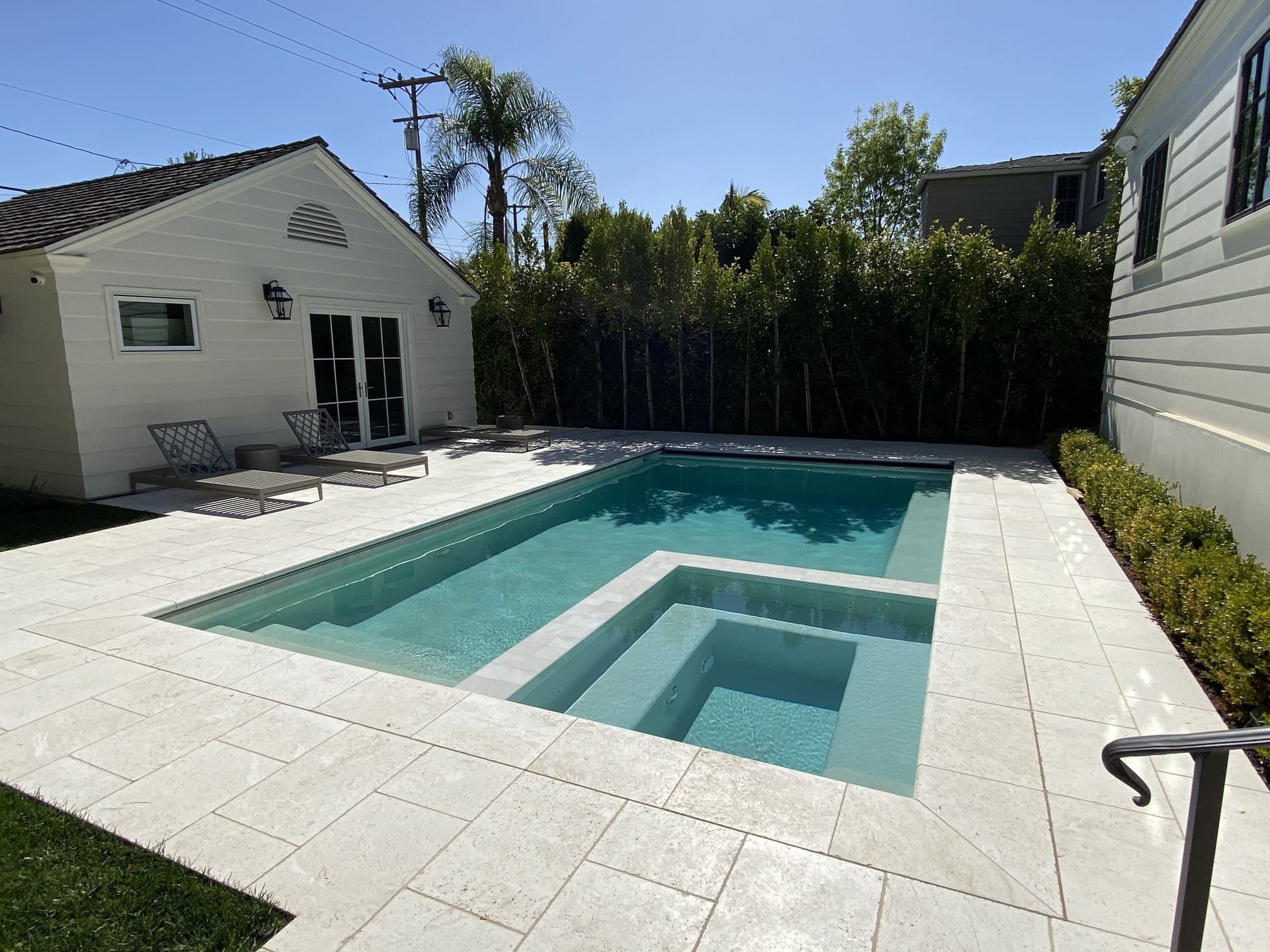 New backyard swimming pool and spa installation with light stone decking on North Sierra Drive in Beverly Hills