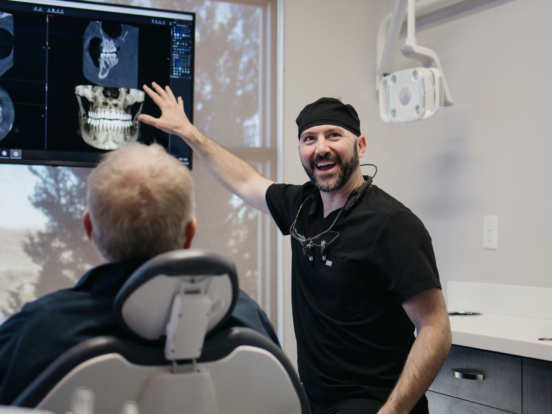 Periodontist discussing a tooth extraction and bone grafting plan with a patient in Denver, CO