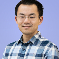 Man with short black hair wearing glasses and a blue plaid shirt smiling against a light purple background.