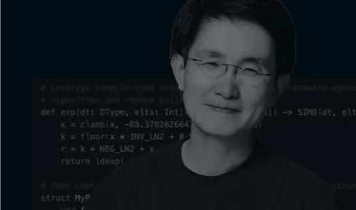 Portrait of a smiling man wearing glasses and a dark shirt with programming code blurred in the background.