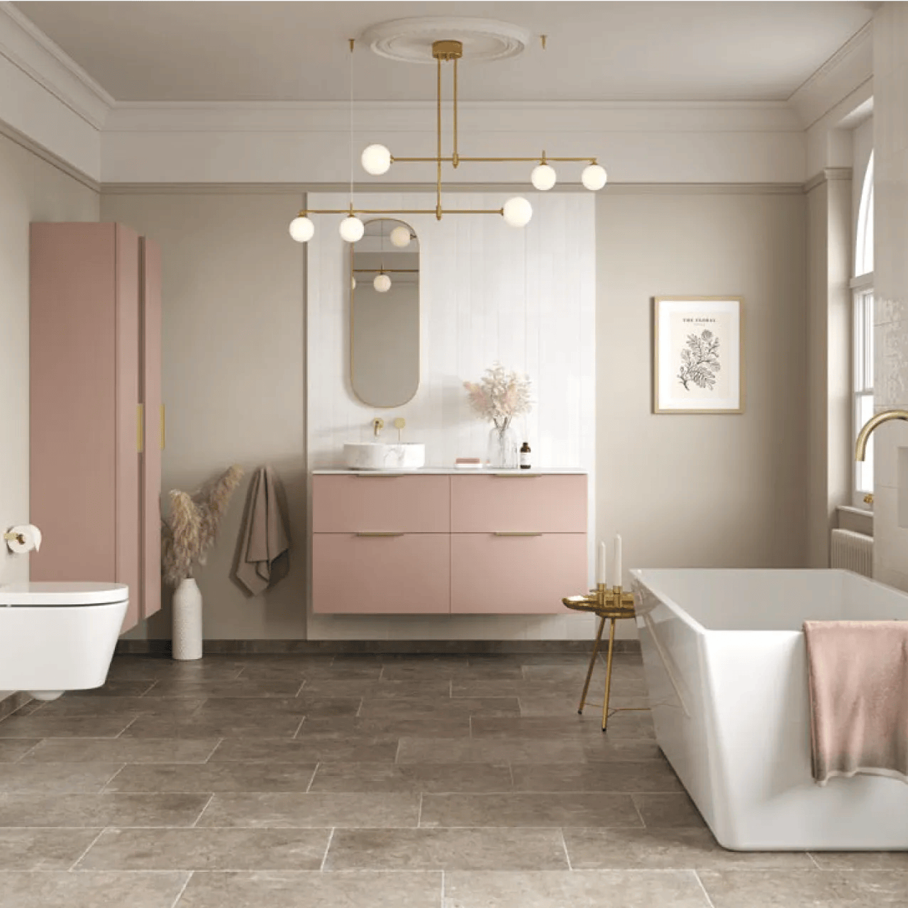 Modern bathroom with beige walls, pink vanity and cabinet, white bathtub, and gold fixtures under a brass chandelier.
