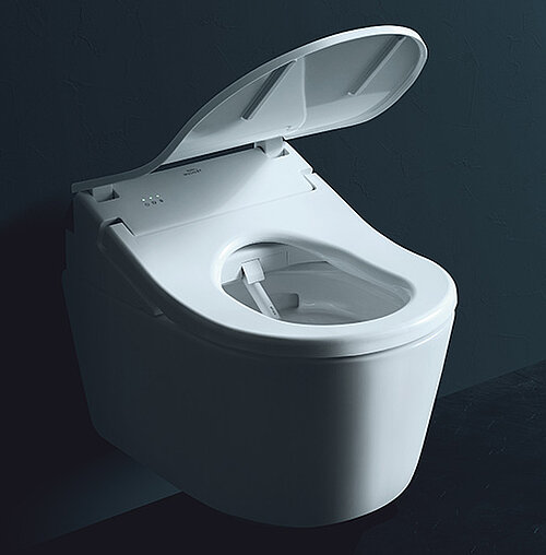 Modern white wall-mounted smart toilet with the lid open against a dark wall.