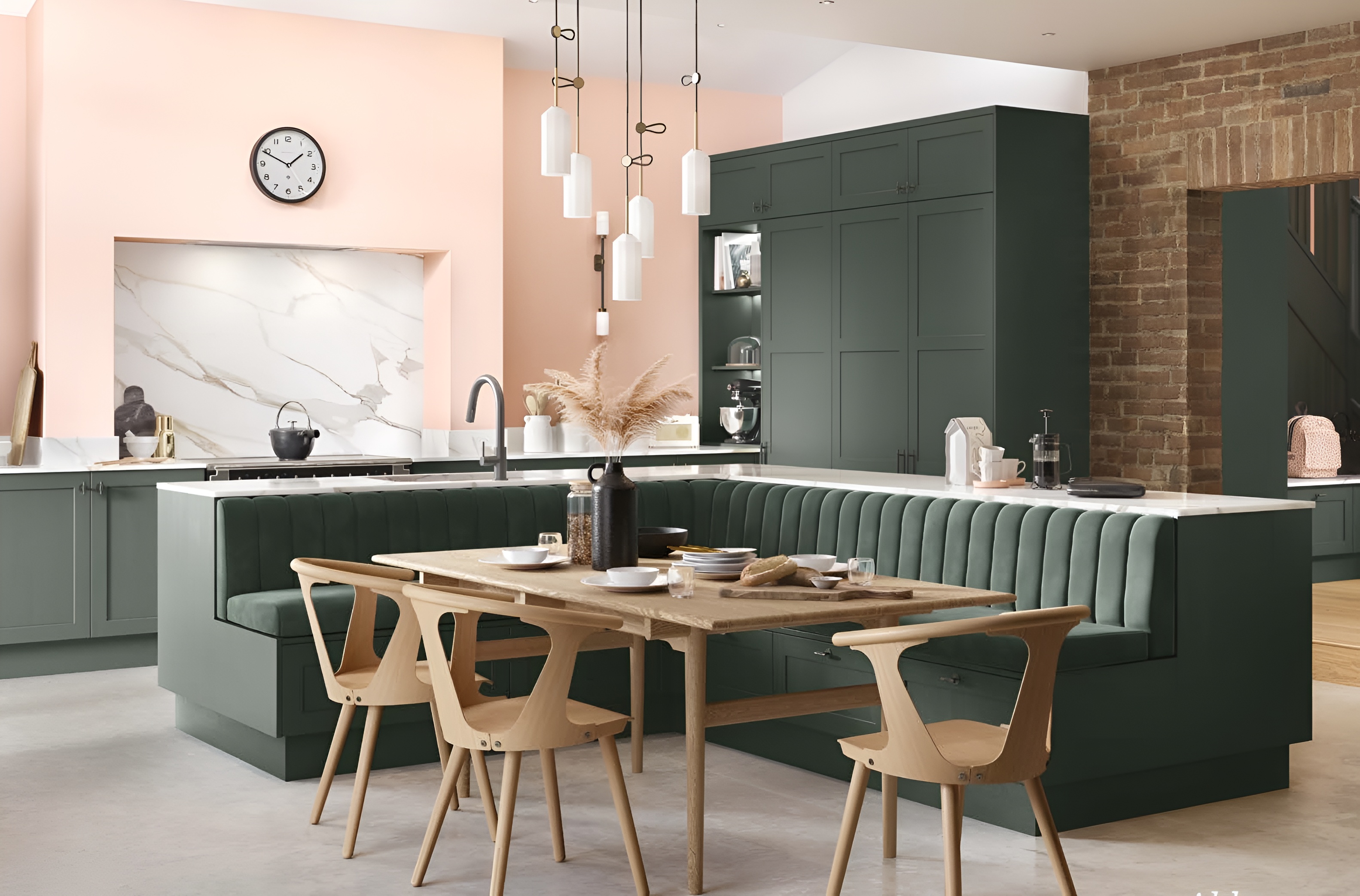 Modern kitchen with green cabinetry, marble backsplash, pink walls, and an L-shaped green banquette around a wooden dining table with wooden chairs.