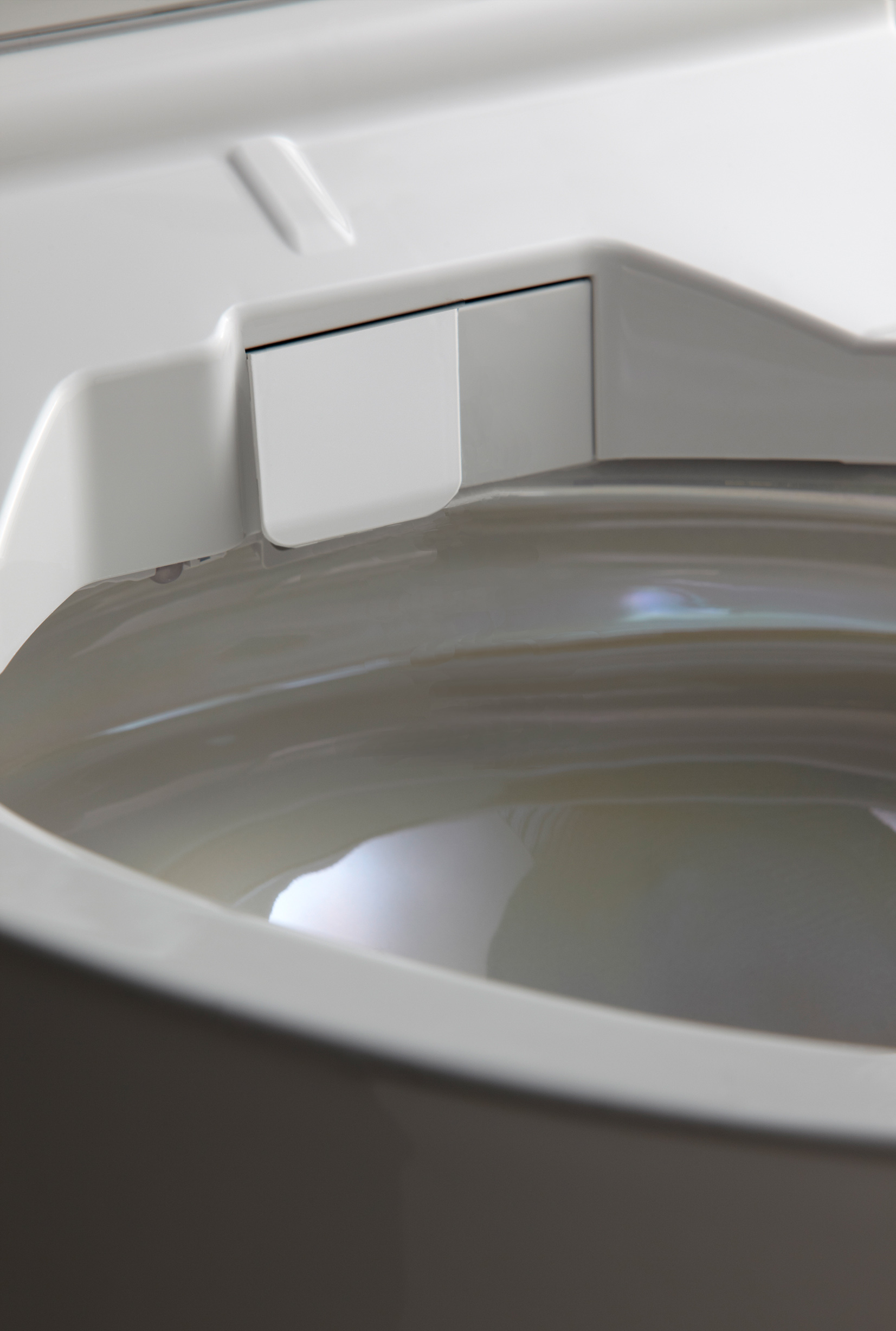 Close-up of a white toilet bowl with water and a clean nozzle cover inside.