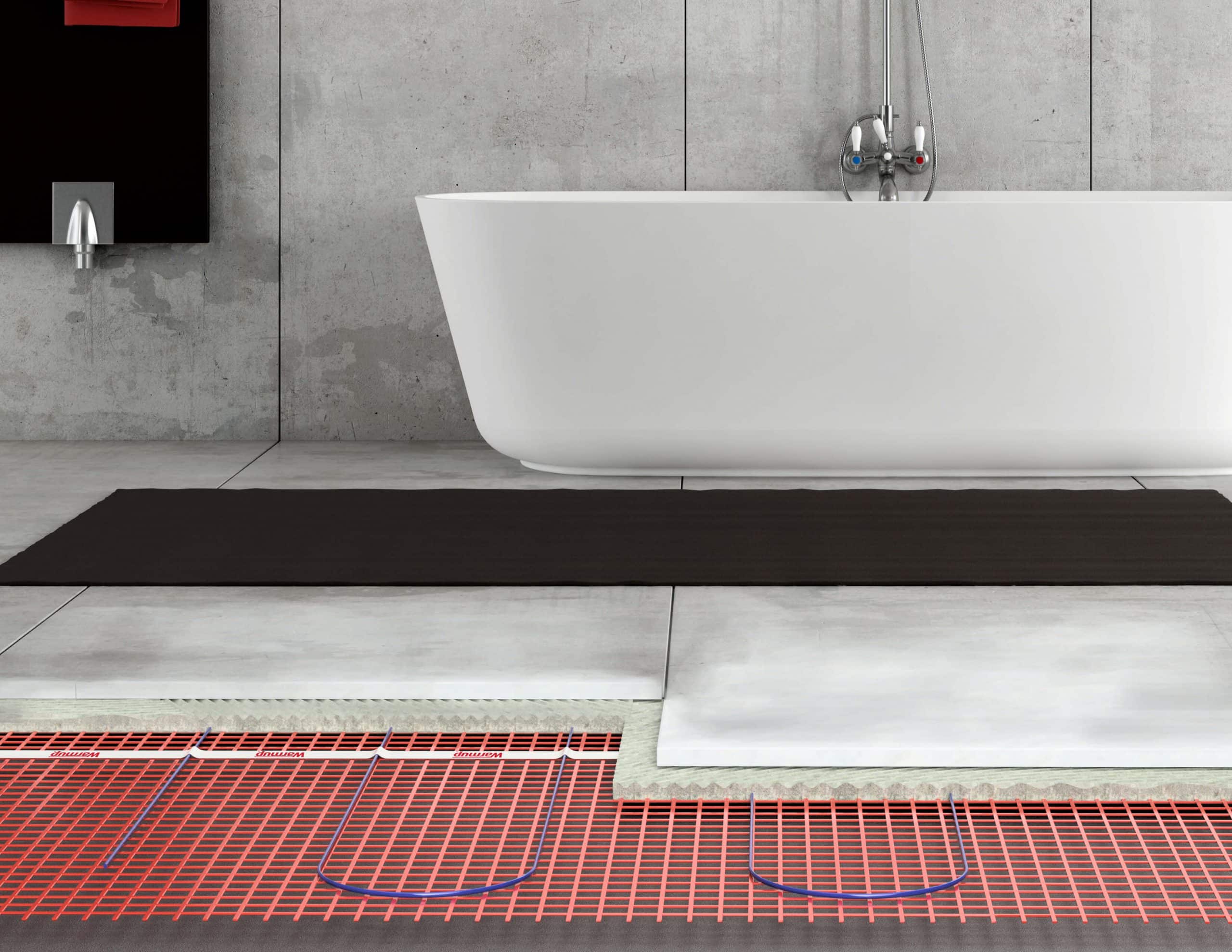 Modern bathroom with a white freestanding bathtub and a black floor mat, showing an underfloor heating system beneath the tiles.
