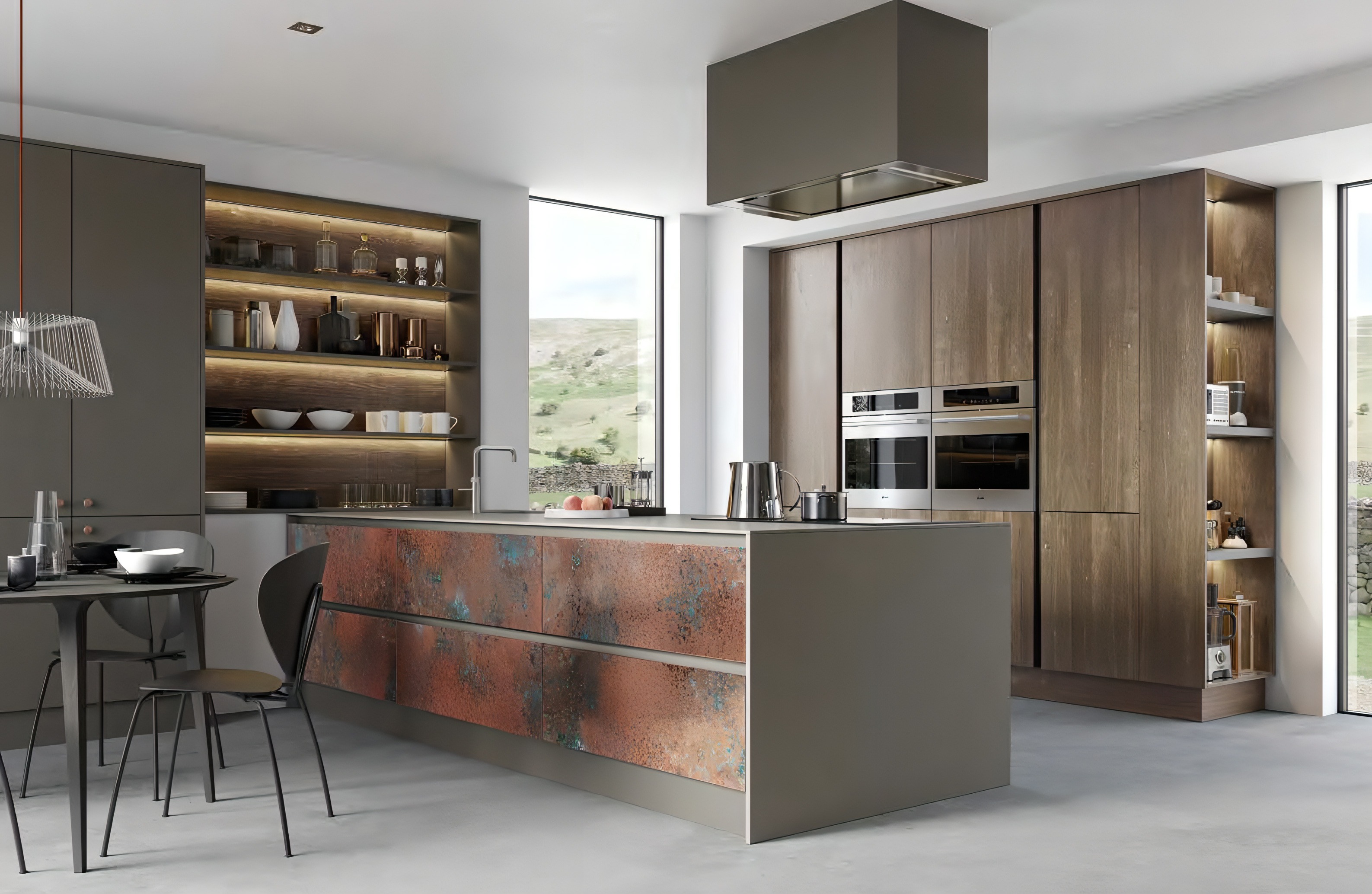 Modern kitchen with a large island featuring rusted metal panels, wooden cabinets, built-in ovens, open shelves, and a dining table with black chairs.
