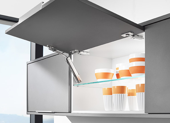 Open modern kitchen cabinet with a glass shelf holding white and orange striped cups and bowls.