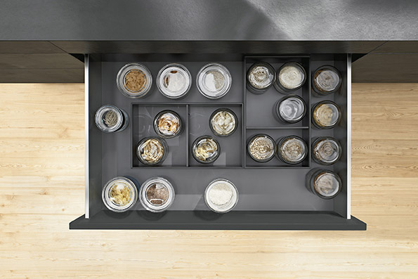 Open kitchen drawer with neatly organized glass jars containing various spices and seasonings.