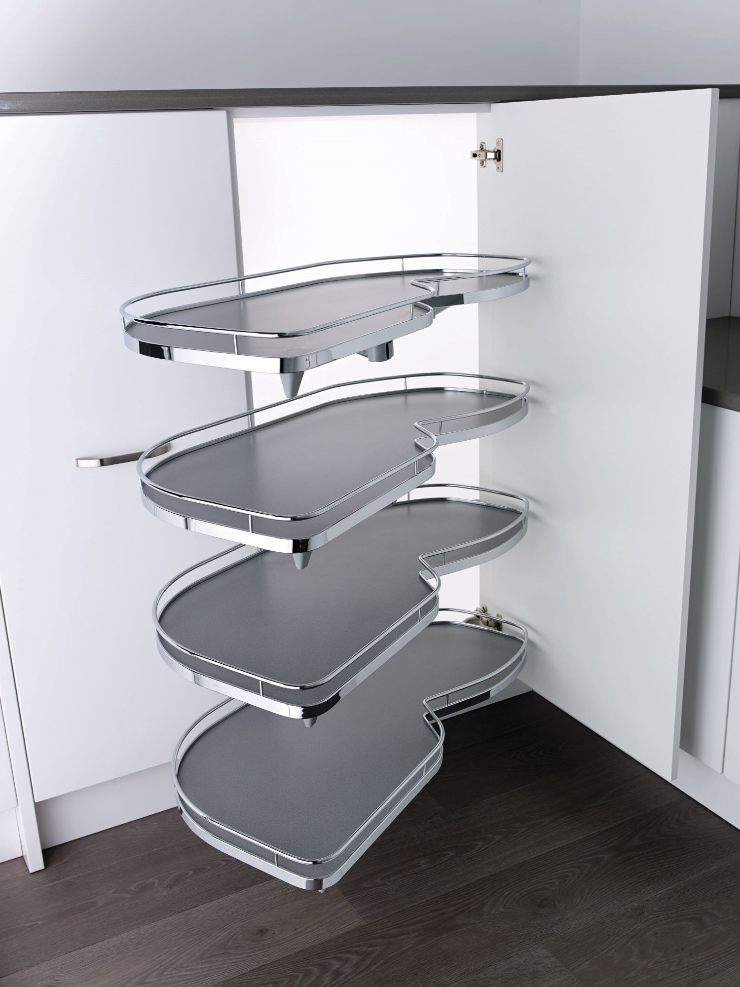 Four-tier kidney-shaped pull-out metal shelves installed inside a white kitchen cabinet.