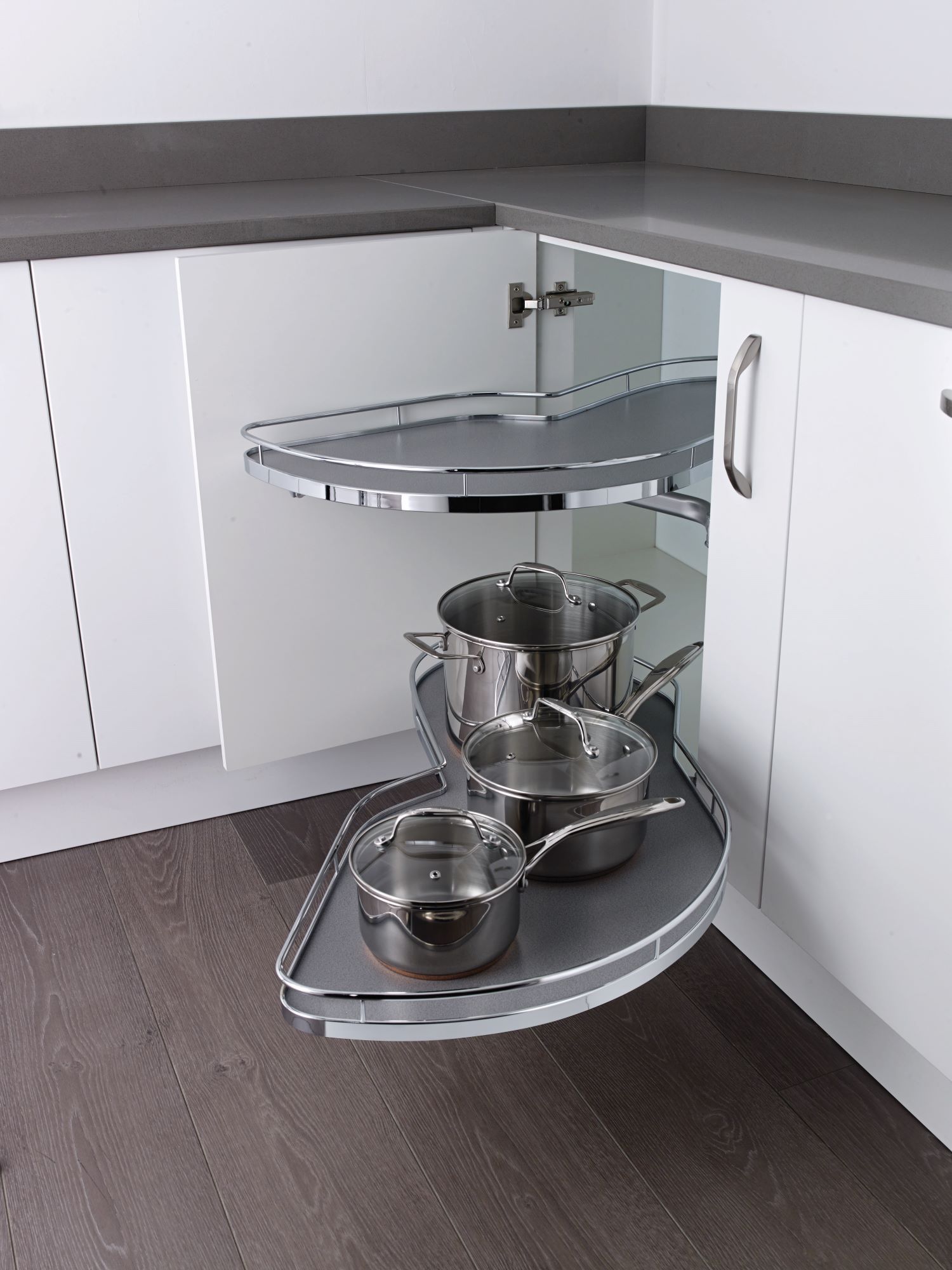 Corner kitchen cabinet with two pull-out rotating shelves holding three stainless steel pots with lids.