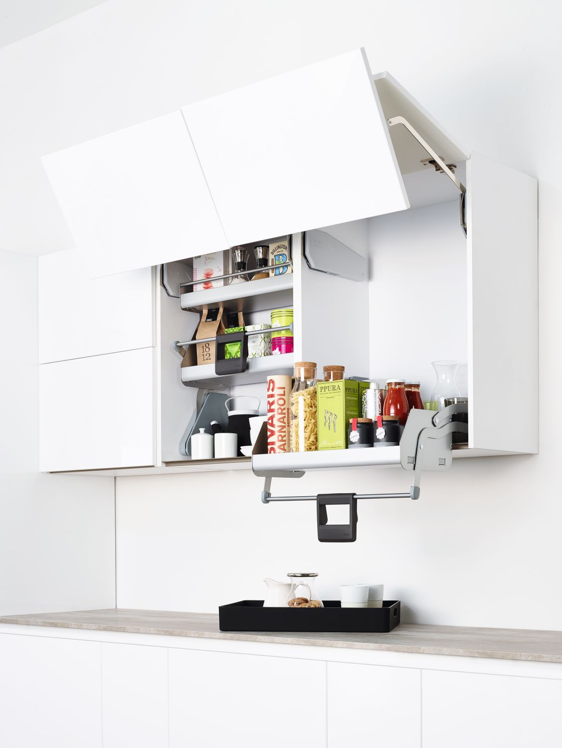 Open white kitchen cabinet with two upward-opening doors revealing organized shelves with jars, boxes, and condiments.